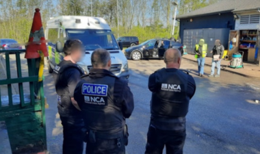 Three officers standing at a carwash with a police van in the background